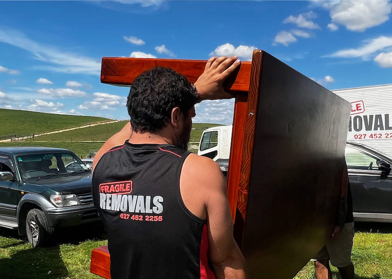 Waikato movers carefully moving dining table during house relocation in Hamilton