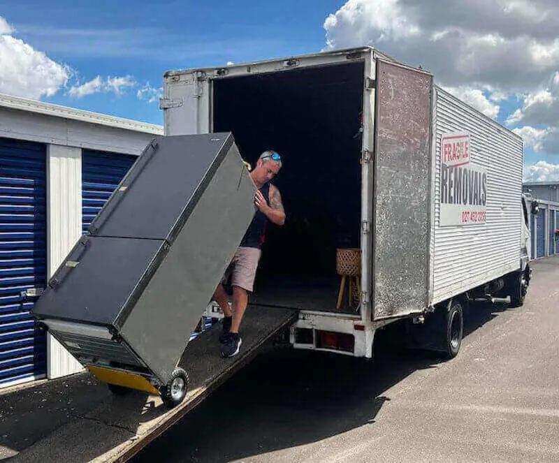 A mover using a trolley to move a fridge up the ramp into a truck for Hamilton relocation