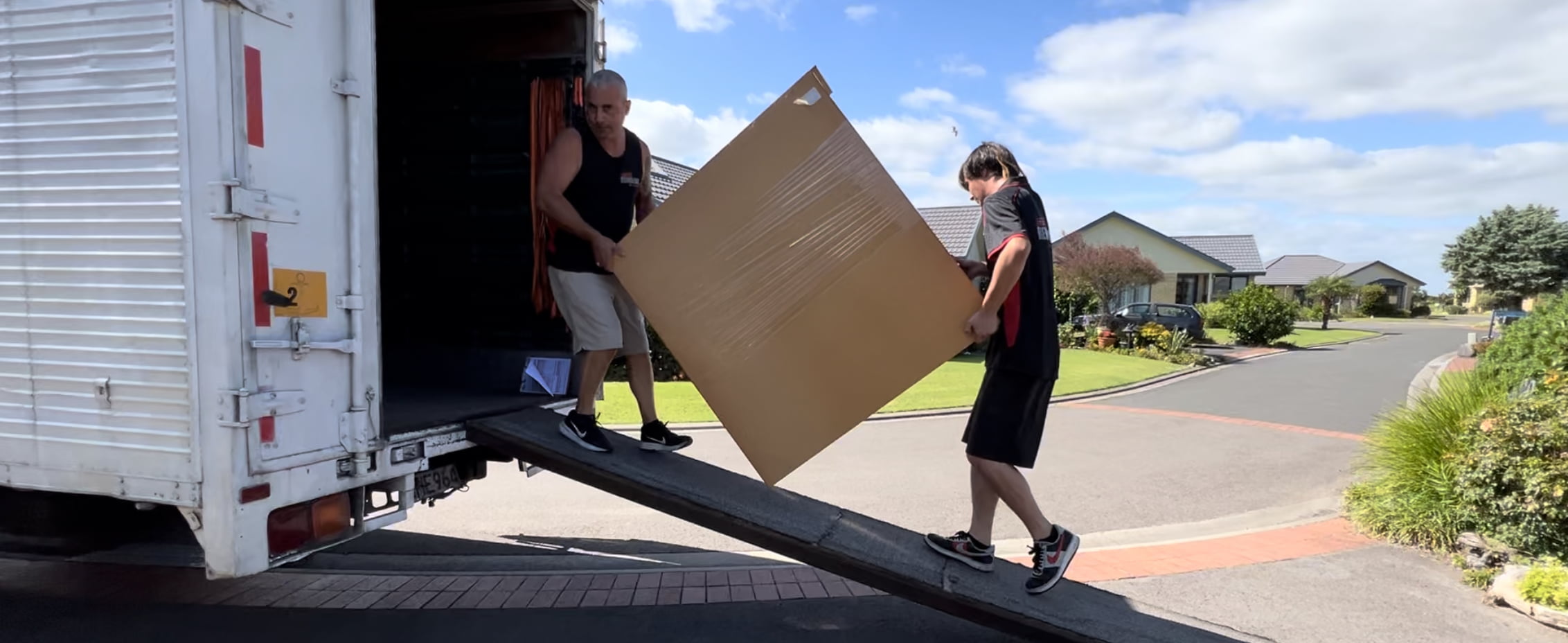 Two Wellington movers carrying a dresser up a ramp into a truck for a Wellington relocation